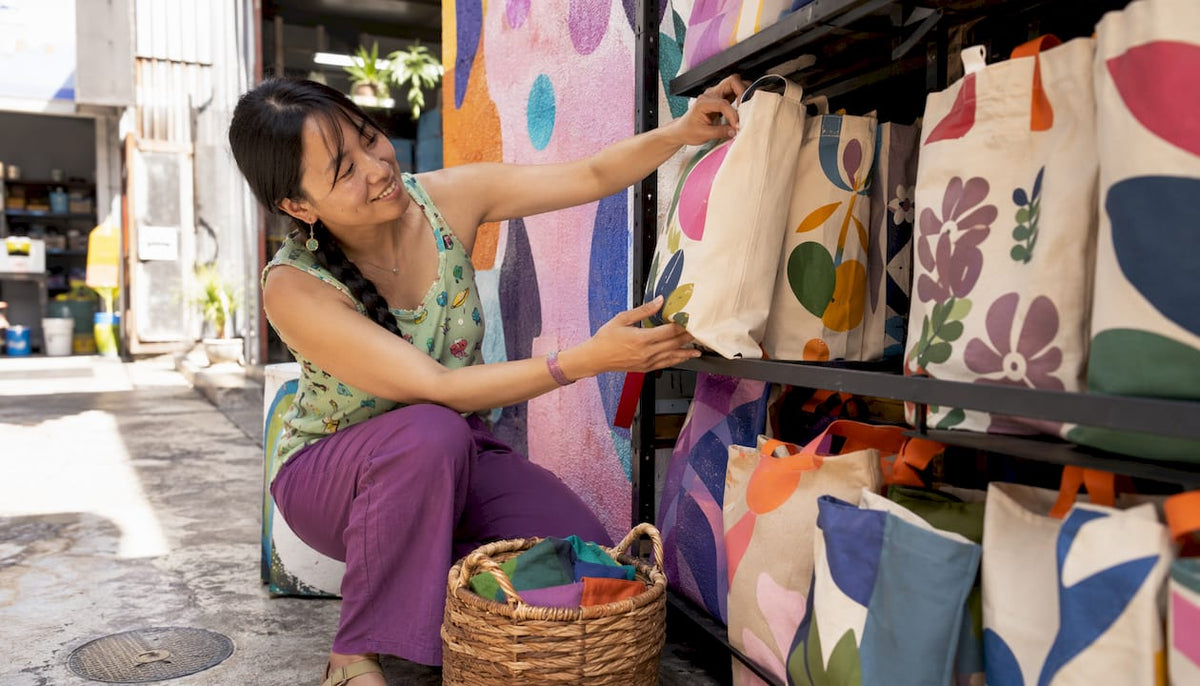 Woman arranging custom tote bags display in store